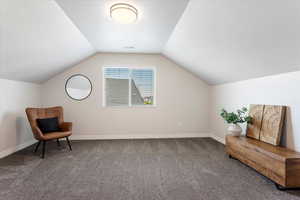 Living area with vaulted ceiling, carpet floors, visible vents, and baseboards