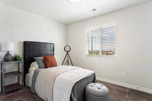 Bedroom with visible vents, dark carpet, and baseboards