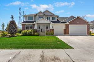 Craftsman-style home with a garage, driveway, a front lawn, board and batten siding, and brick siding