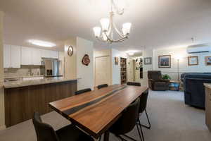 Dining room featuring a wall mounted AC, carpet flooring, and an inviting chandelier