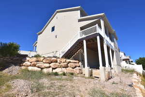 View of home's exterior with fence, a deck, and stairs