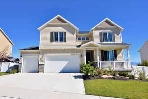 View of front of property featuring an attached garage, covered porch, fence, and concrete driveway