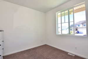 Carpeted spare room with plenty of natural light, visible vents, and baseboards