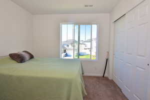 Carpeted bedroom with a closet, visible vents, and baseboards