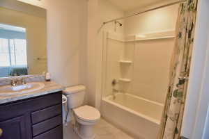 Bathroom with shower / tub combo, vanity, toilet, and tile patterned floors