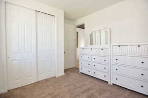 Unfurnished bedroom featuring a closet and light colored carpet