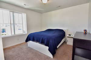 Bedroom with light carpet, a textured ceiling, visible vents, and baseboards