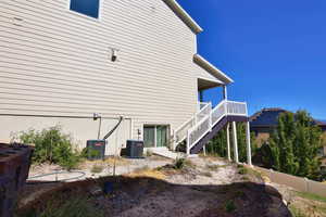 View of property exterior with stairs, fence, and central AC