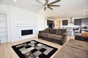 Living area with light wood-style floors, a fireplace, visible vents, and recessed lighting