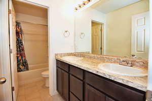 Full bath with double vanity, a sink, toilet, and tile patterned floors