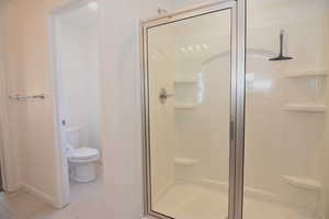 Full bath with a stall shower, tile patterned flooring, and toilet