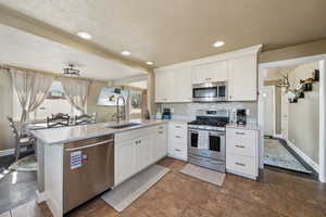 Kitchen with a peninsula, a sink, white cabinets, and appliances with stainless steel finishes