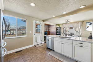 Kitchen with white cabinets, appliances with stainless steel finishes, a textured ceiling, and a sink