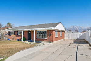 Ranch-style house with a mountain view, brick siding, fence, roof with shingles, and a front yard