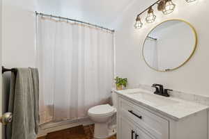 Bathroom with toilet, shower / tub combo, and vanity