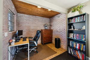 Office with brick wall, wood ceiling, and recessed lighting