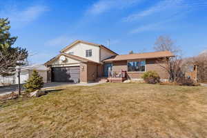 View of front of home with a garage, a front yard, brick siding, and driveway