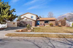 View of front of house featuring a garage, driveway, brick siding, and a front lawn