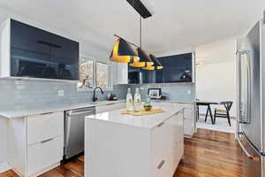 Kitchen with appliances with stainless steel finishes, dark wood-style flooring, modern cabinets, and a sink