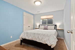 Carpeted bedroom featuring visible vents, baseboards, and a closet