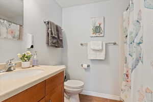 Bathroom featuring baseboards, toilet, tile patterned floors, curtained shower, and vanity