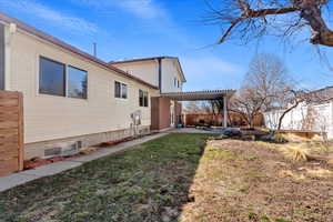 Rear view of property with a yard, fence, a pergola, and a patio