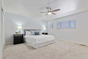 Bedroom featuring light carpet, ceiling fan, visible vents, and baseboards