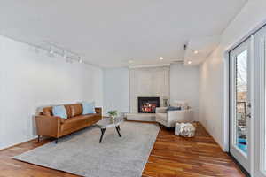 Living room featuring a brick fireplace, track lighting, wood finished floors, and recessed lighting