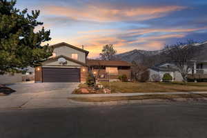 View of front of house featuring a garage, brick siding, driveway, and a lawn