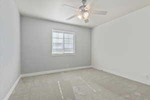 Carpeted spare room featuring visible vents, baseboards, and a ceiling fan