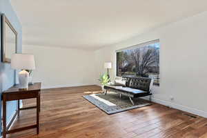 Living area with visible vents, baseboards, and wood finished floors