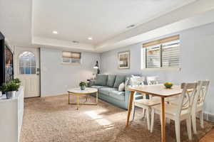 Carpeted living area with baseboards, a tray ceiling, visible vents, and recessed lighting