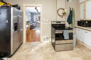 Kitchen featuring white cabinets, visible vents, stainless steel appliances, and light countertops