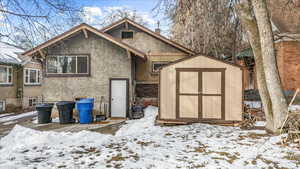 Exterior space with stucco siding, a chimney, a storage unit, an outdoor structure, and brick siding