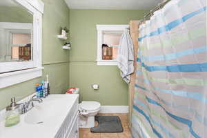 Full bathroom featuring baseboards, toilet, a shower with curtain, tile patterned floors, and vanity