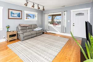 Living room with rail lighting, visible vents, and wood finished floors