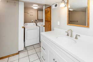 Washroom featuring a textured ceiling, visible vents, a sink, and independent washer and dryer