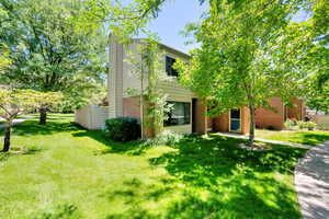 View of front facade with brick siding, a chimney, and a front lawn