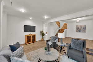 Living area featuring light wood-style flooring, stairway, ornamental molding, and recessed lighting