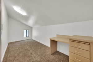 Unfurnished office with lofted ceiling, carpet, and built in study area