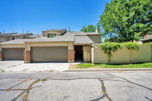 View of front of house featuring a chimney, brick siding, roof with shingles, a garage, and concrete driveway