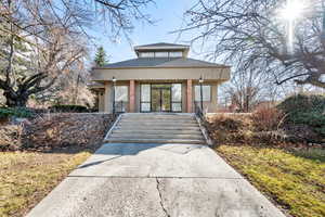 View of front of property with stucco siding, roof with shingles, and covered porch