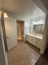 Bathroom featuring vanity, crown molding, a textured ceiling, and light tile patterned floors