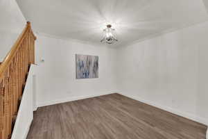 Unfurnished room with a chandelier, wood finished floors, and crown molding