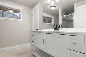 Bathroom featuring marble finish floor, a stall shower, vanity, and baseboards