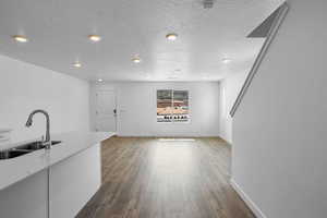 Kitchen with a textured ceiling, dark wood finished floors, a sink, and light countertops