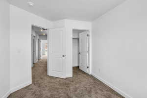 Unfurnished bedroom featuring carpet floors, baseboards, and a textured ceiling