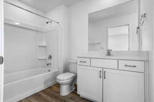 Bathroom with shower / bathtub combination, vanity, toilet, and wood finished floors