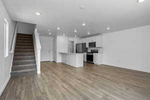 Kitchen with a peninsula, stainless steel appliances, wood finished floors, and open floor plan