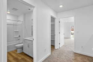 Full bath featuring visible vents, shower / bathing tub combination, toilet, vanity, and baseboards